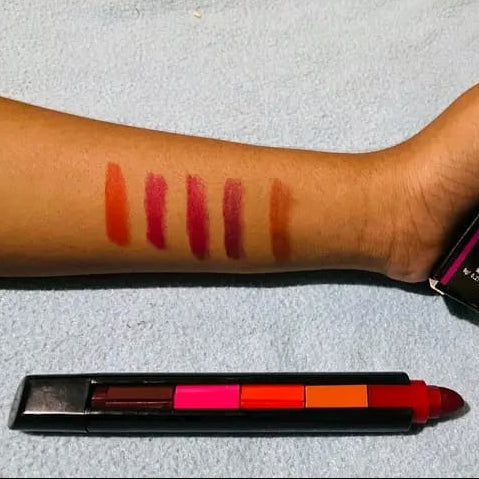 Lipstick swatches on a person's arm with a lipstick palette below